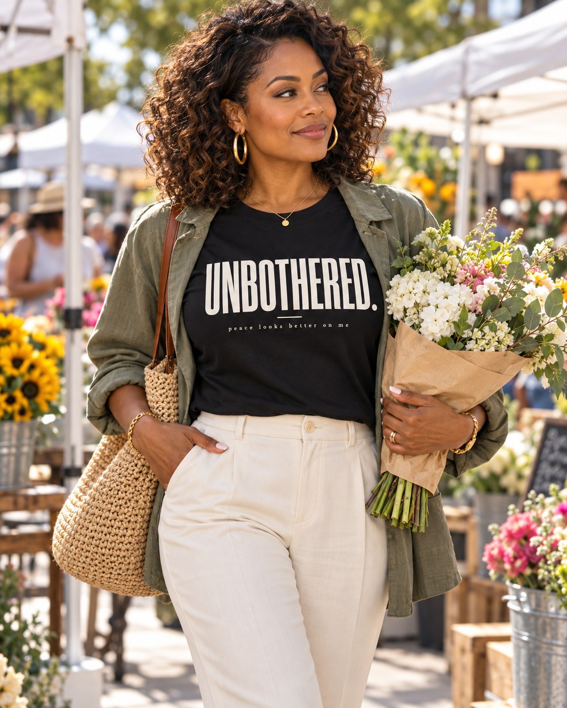 Woman at an outdoor market wearing an Unbothered. Peace looks better on me. tee